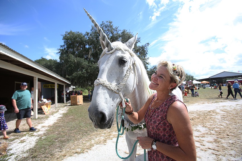 Caroline Williams walks Cherish the unicorn around the festival.