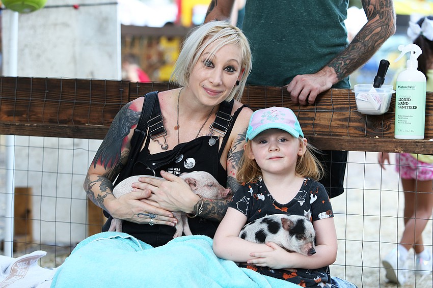 Megan and Astrid Buchanan play with piglets.
