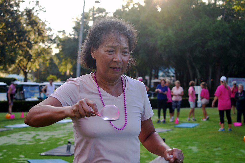 Sheila Colletta balances a water balloon on a spoon during a relay race. The race was one of the activities in the fitness boot camp during University Park Country Club's Pink Week.