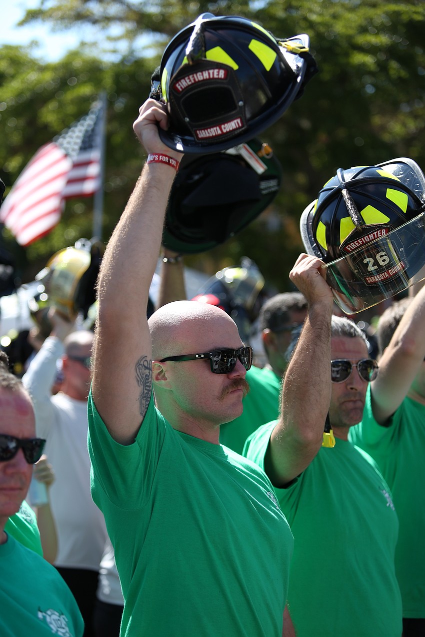 Dillon Wade with Station 26 raises his helmet in support.