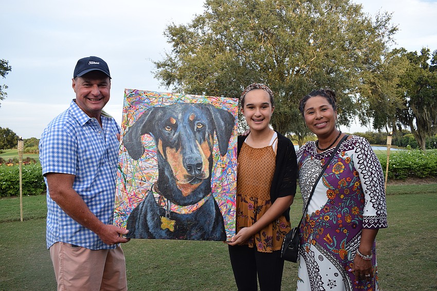 Lakewood Ranch's Gene Storm, Emily Storm and Bee Storm love the painting they purchased in an auction because it looks like their family dog, Stella.
