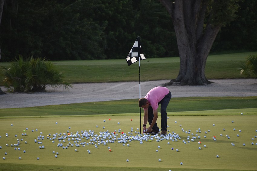 Patrick Gogoel, the head pro at Ritz-Carlton Member Golf Club, finds the ball at the bottom of the hole to see who won $500 from the helicopter ball drop.