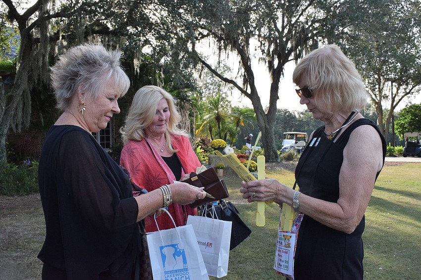 Lakewood Ranch's Bonnie Frye and Debbie Allen buy raffle tickets from Carol Ohlendorf of the Humane Society at Lakewood Ranch.