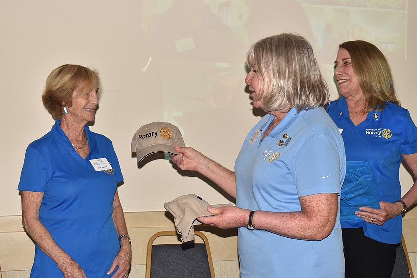 Carol Erker, hands Jan Wallace her welcome to Rotary gifts.