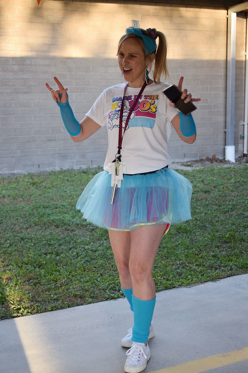 Kate Messer, a first grade teacher dressed for the '80s, greets students as they walk to class.