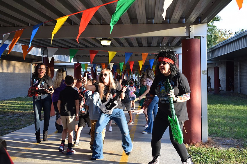 Kindergarten teachers Fran Vila, Kaehla Eidson and Claire Martin rock out as students walk to school. The teachers were dressed for the 1980s.