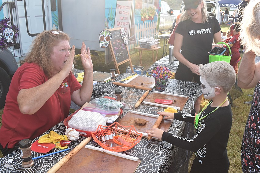 Colton Boley (right) of Sarasota rolls a clay figure that would be shaped into a ghost with some encouragement of Pure Imagination Studio owner Kristi Mezick (left) on Tuesday night.