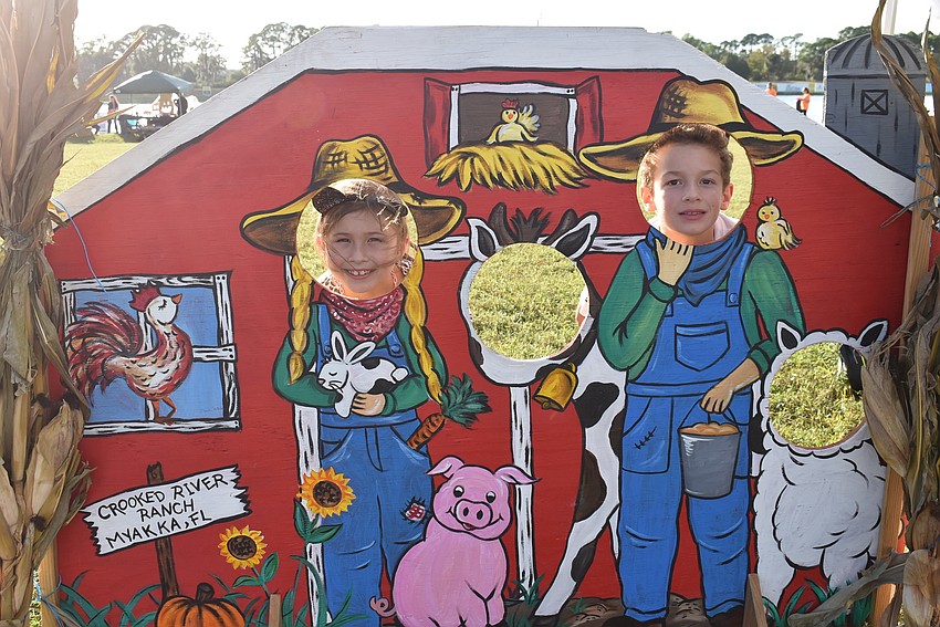 Violet Plank (left) of Lakewood Ranch and Vincent Merucci of Sarasota poke their heads through a cutout of farmers at Tuesday night's event at Nathan Benderson Park.