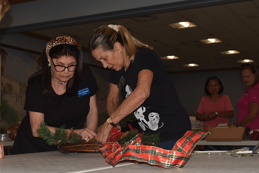 Jane Monaghan and Karen Iamello wrap a wreath in ribbon.