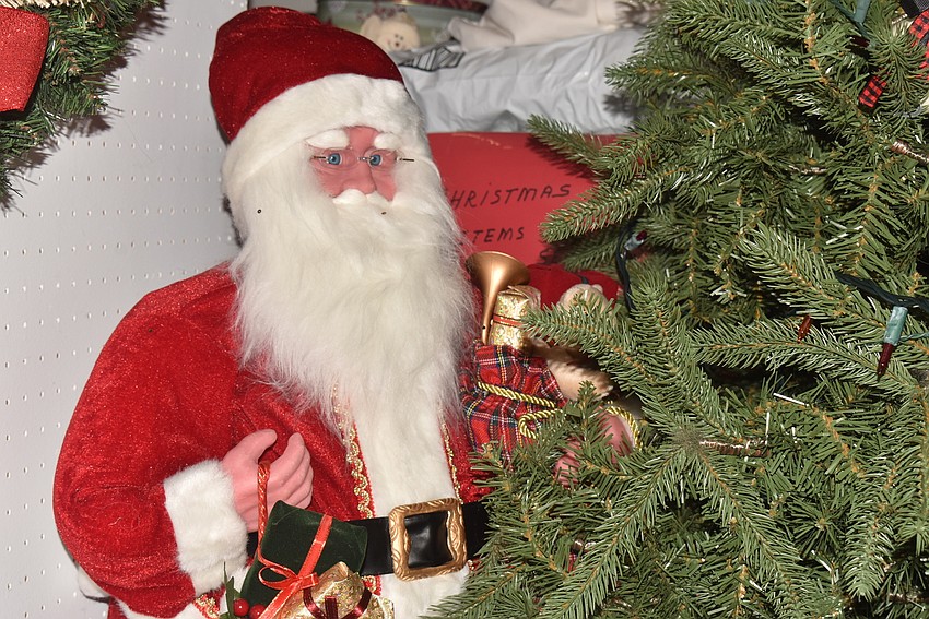 A Santa statue helps trim the tree.