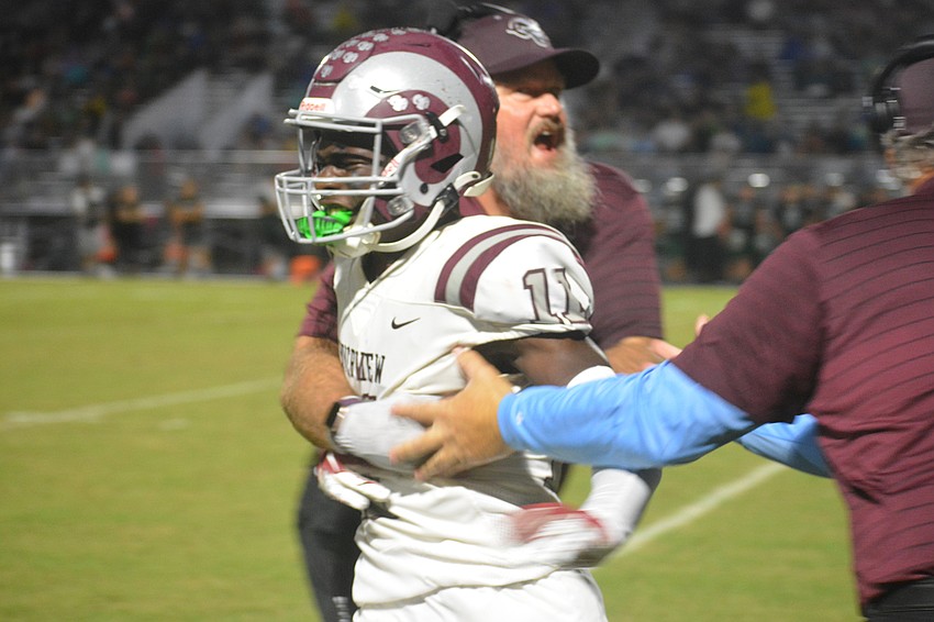 Rams senior Johnell Williams celebrates with coaches after his second-quarter touchdown catch.