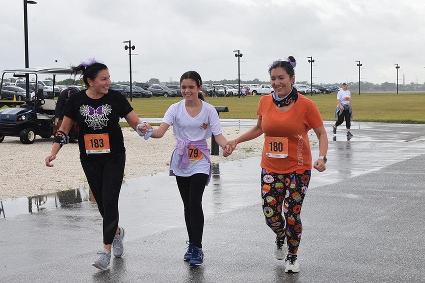 Sarasota's Becky Barnes, Sophia Curtis, who is 10 years old, and Jessica Curtis cross the finish line together. The Boo Run was Sophia Curtis' first 5K.