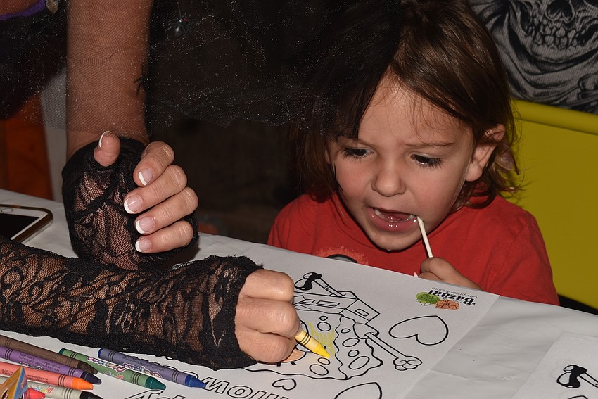 Zayden McCurdy enjoys a lollipop while coloring with Pam McCurdy.