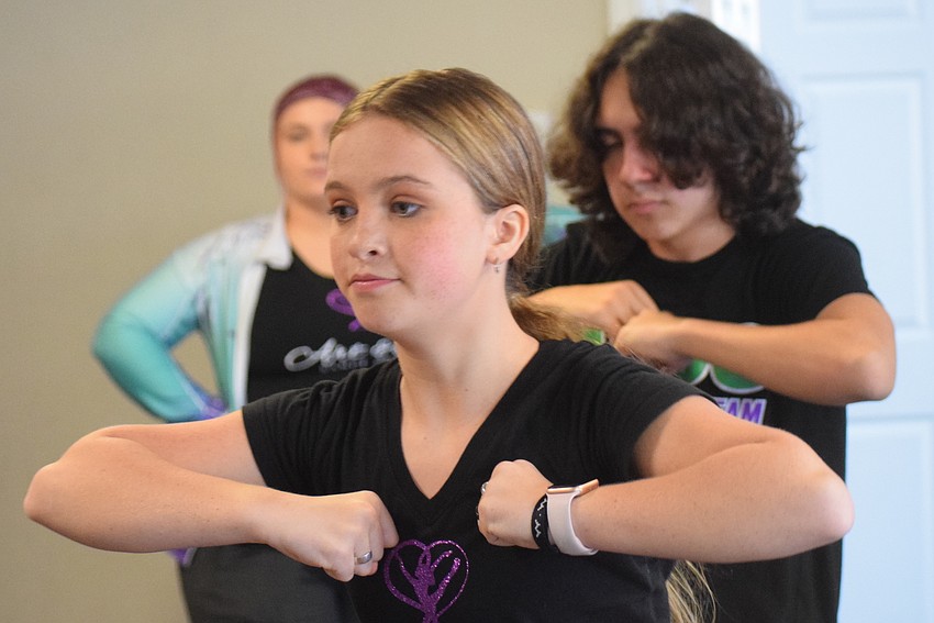 Hayden Schmidt works on a routine with Anthony Longo in the back.