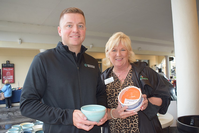 Andy Guz, the CEO of Lakewood Ranch Medical Center, and Maribeth Phillips, the president and CEO of Meals on Wheels Plus of Manatee, show off the ceramic bowls people are able to choose after selecting their soup.