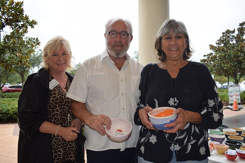 Maribeth Phillips, the CEO and president of Meals on Wheels Plus of Manatee, helps Heritage Harbour's Steve Gandel and Paulette Gandel pick out their bowls to take home.