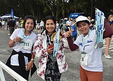 Piyachat Dobbs, Poonsita Geden and Tuanchai Boonnoen of Lakewood Ranch greeted finishers of Saturday's Fort Hamer Bridge run with medals, some music from a tambourine and big smiles.