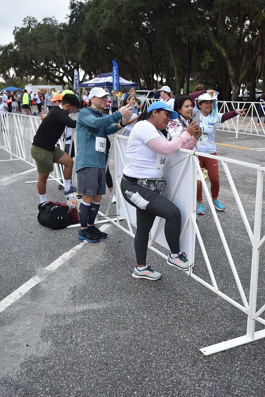 After finishing the race themselves, several runners stood along the fence near the final stretch to encourage others as they finished the annual Fort Hamer Bridge run on Saturday.