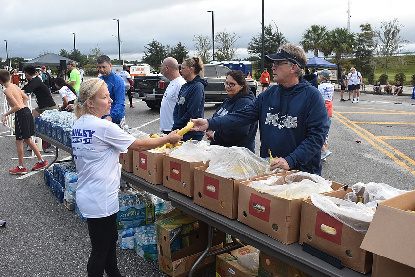 Greg Sutton (right) of Parrish. hands out bananas and water to runners just after they finished the Fort Hamer Bridge Run on Saturday morning.