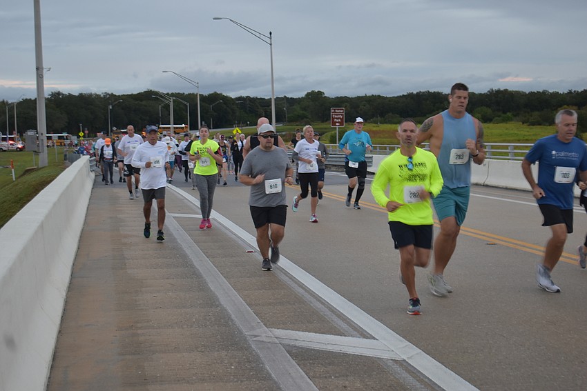 Runners make their way up and over the Fort Hamer Bridge just after the start of Saturday morning's event in Parrish.