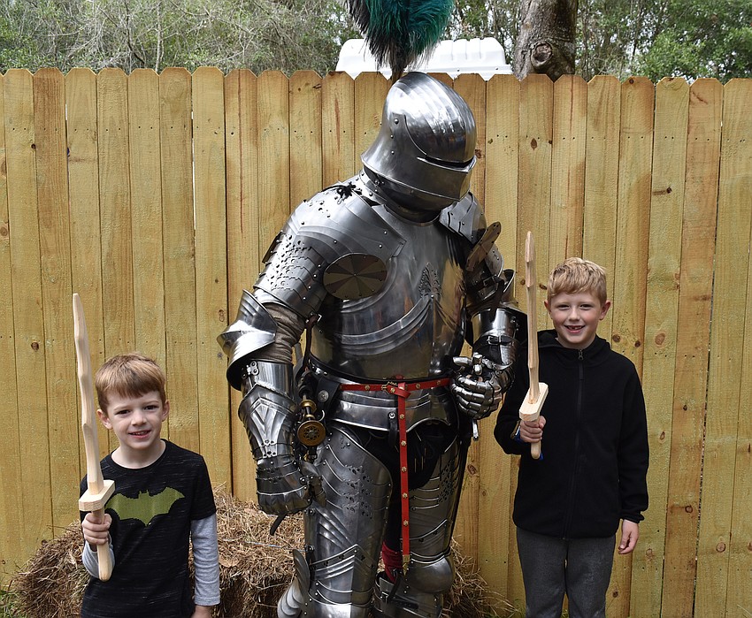 Parker and Mason Barnhart of Lakewood Ranch show off their new swords to a knight at the Sarasota Medieval Fair on Saturday.