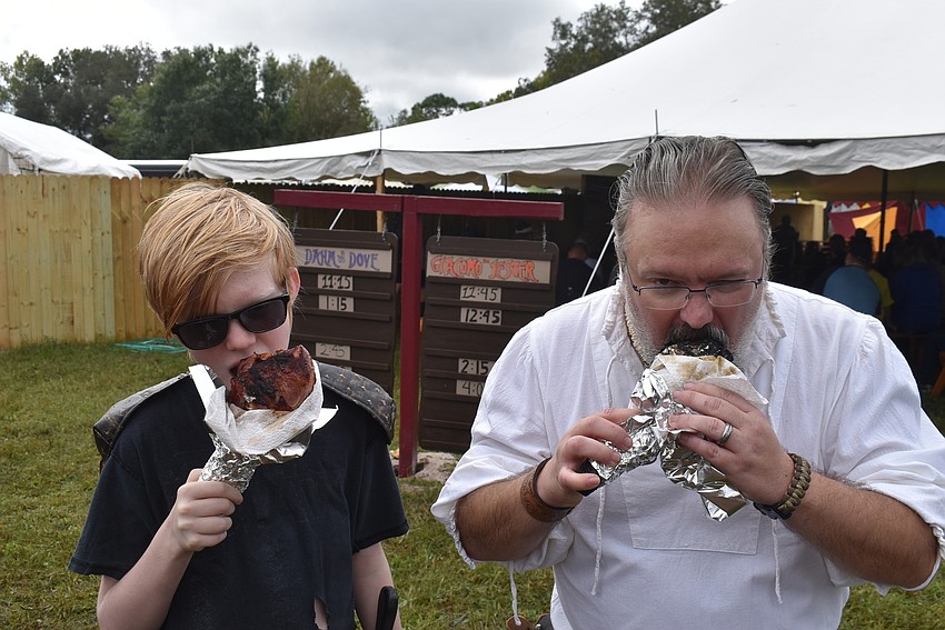 Domanik and Christopher Gabel of Sarasota scarf down turkey legs — a traditional fan-favorite snack — at the Medieval Fair.