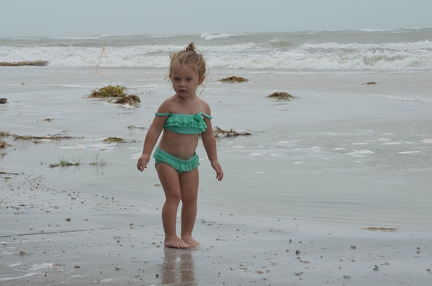 Riley Tchouros, 2, from Memphis, approaches the surf as it laps at the driveways of the rental homes along Beach Road.
