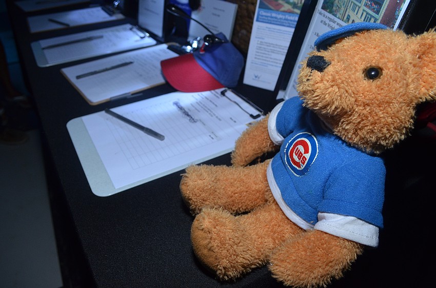 Silent auction items line tables by the dance floor. The Cubs package featured a Cubs hat and teddy bear along with a trip to Chicago (3-night stay and round-trip coach airfare) to use two bleacher seat rooftop tickets to a regular-season game.
