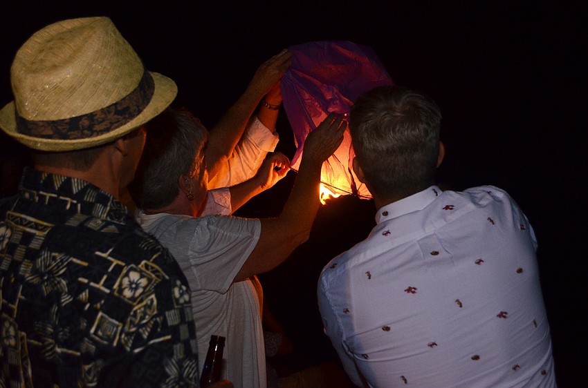 Attendees fight the wind and attempt to release a lantern.