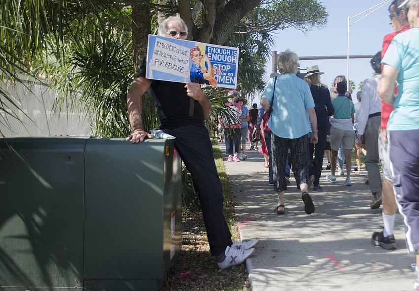 Don Guy holds a sign while marchers make their way from Bayfront Park to the bridge.
