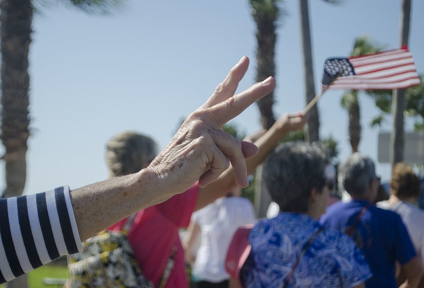 A marcher holds a peace sign while crossing the Ringling Bridge.