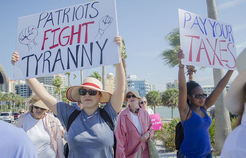 Elizabeth Johnson and Jenny Johnson hold signs while marching across the Ringling Bridge.
