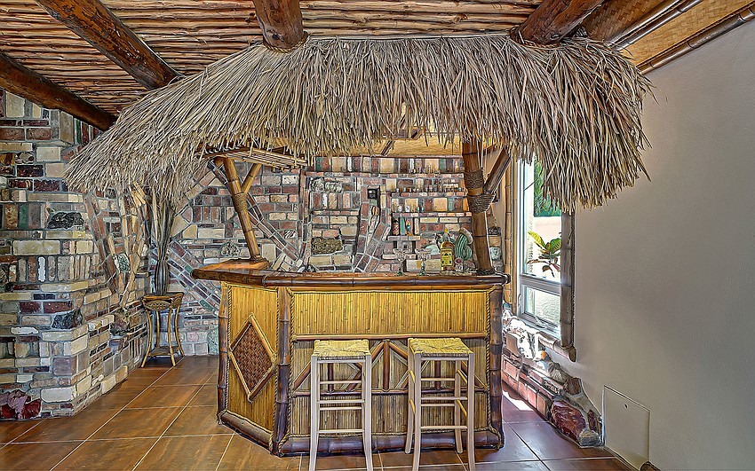 A tiki bar is joined by an outdoor tiki hut.