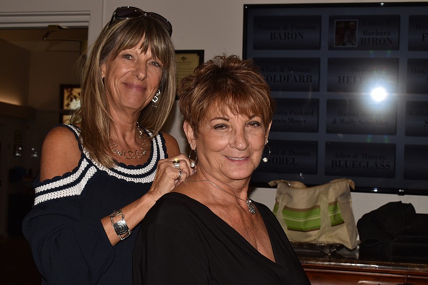 Ronetta Krause fastens a necklace on Dorina Mangan.