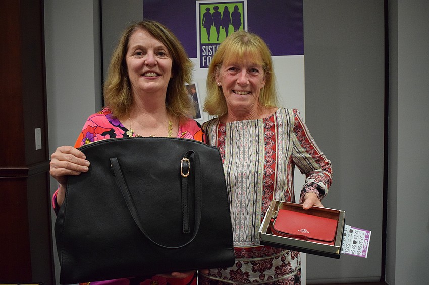 Amy Gorman, president of Sisterhood for Good, presents Lakewood Ranch's Kathleen Osterberg with his Bingo prize during Designer Bag Bingo.