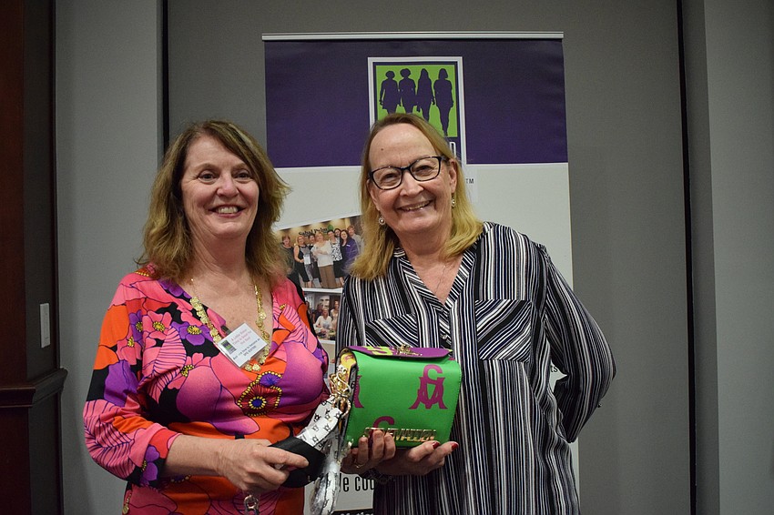Amy Gorman, the president of Sisterhood for Good, presents a designer bag to Bradenton's Carol Mull.