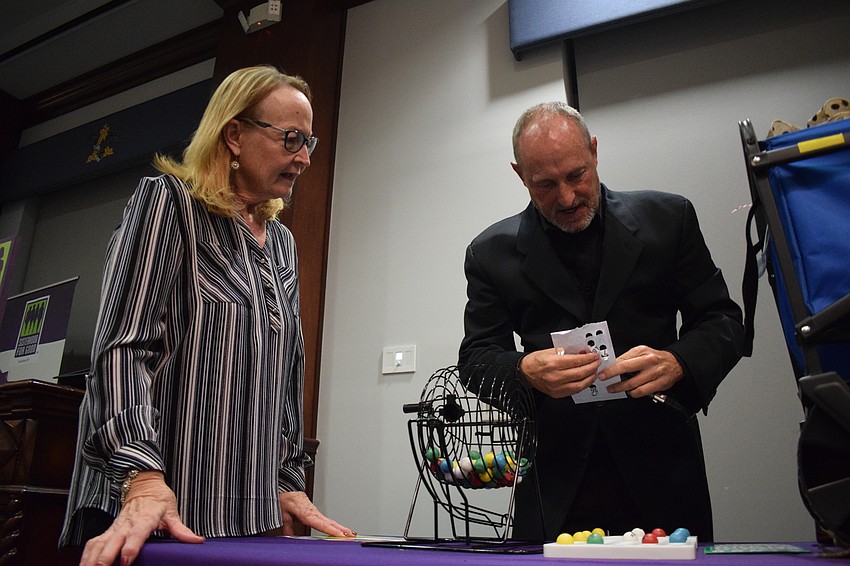 Bradenton's Carol Mull gets her Bingo card checked by Jay Heater, the guest caller and managing editor of the East County Observer, at Designer Bag Bingo.