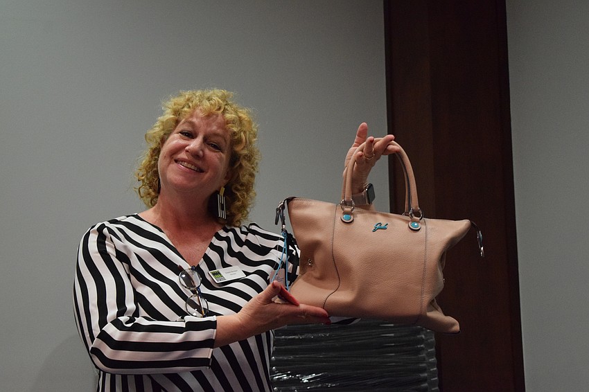 Debbie Breslof, a Sisterhood for Good member, shows off one of the bags available to win during Designer Bag Bingo.