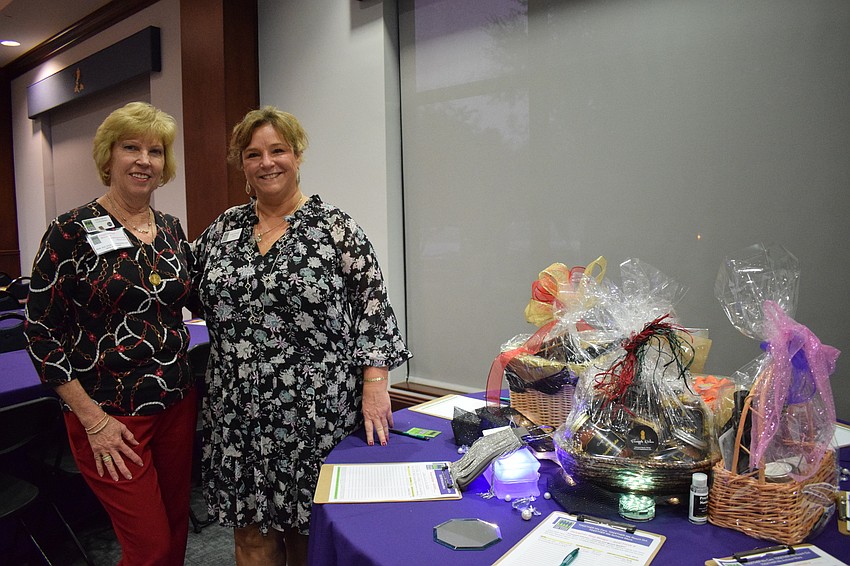 Kathy Collums and Laurel Corriveau, members of Sisterhood for Good, show off the different baskets available in the silent auction.