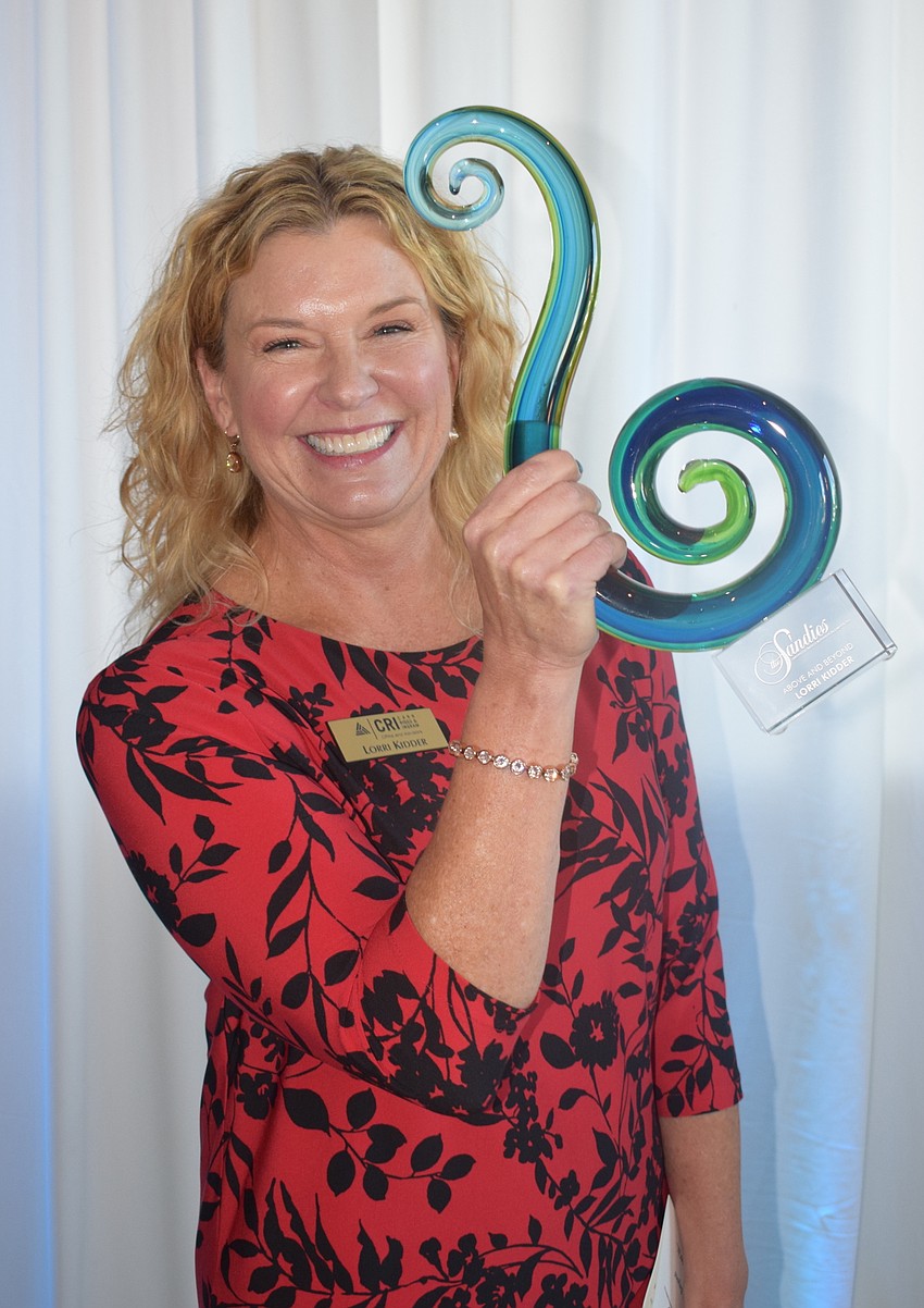 Lorri Kidder of Carr, Riggs and Ingram holds up her Above and Beyond award.