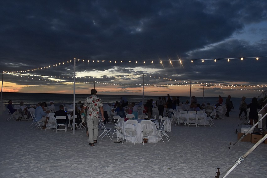 Attendees took plates and glasses of wine out to the gulfside tent.