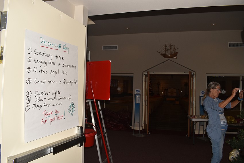 Kathy Kussy trims the angel tree. Church staff hung a sign denoting what the big decorating day goals were.