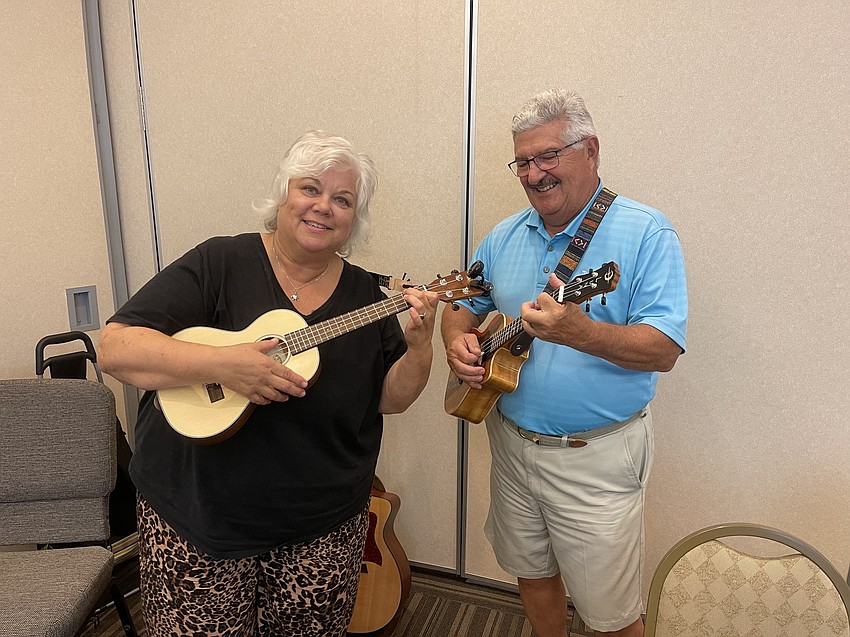 Alice Baumann and Dave Barone get their ukuleles in tune before playing a Christmas song.