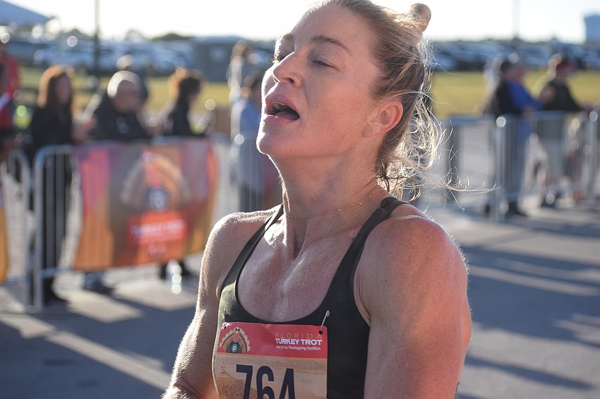 Katie Reynolds of Sarasota shows the pain of going all out to win the women's division of the Florida Turkey Trot at Nathan Benderson Park on Thanksgiving morning.