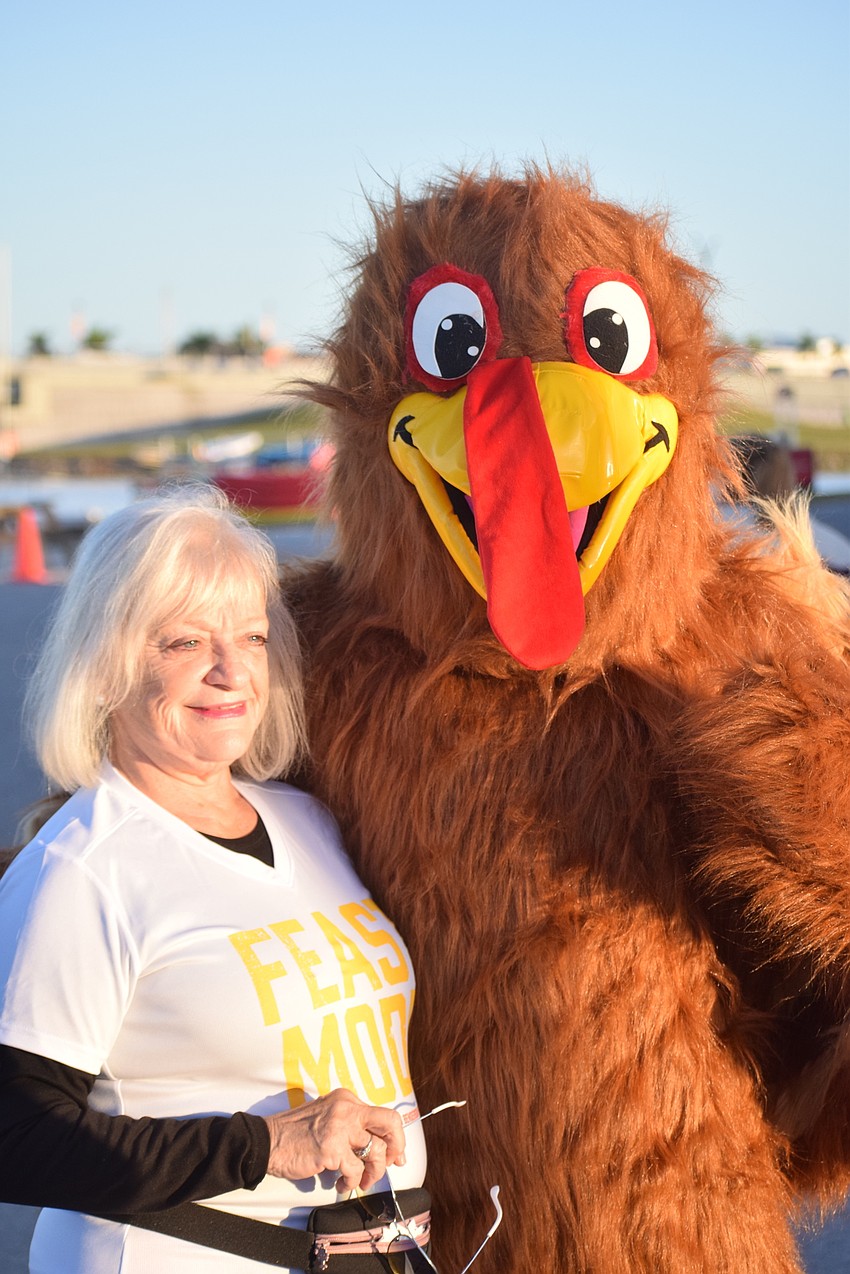 Sarasota's Nancy Cadieux gets a hug from Troy the Turkey at the Florida Turkey Trot at Nathan Benderson Park.