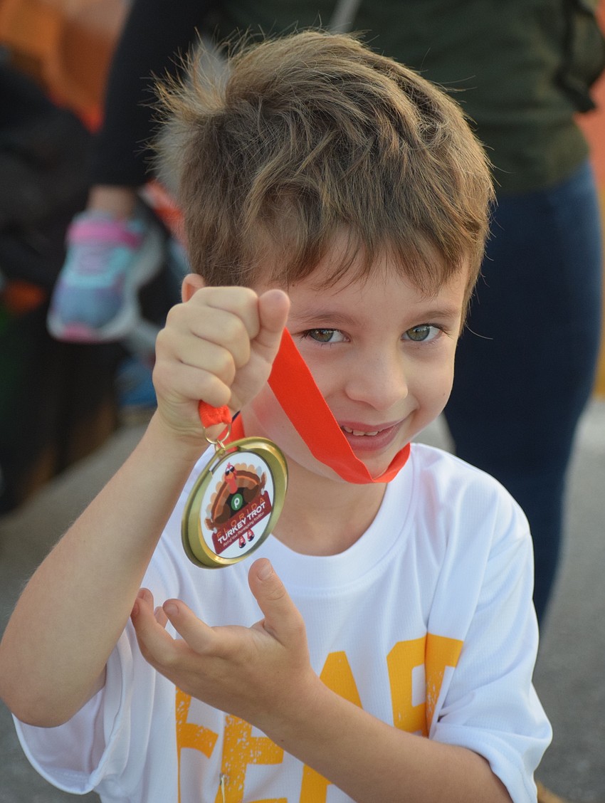 Charleston, South Carolina 4-year-old Isaac Lewis proudly shows off his medal following the Kids Turkey Dash. His family was visiting relatives.