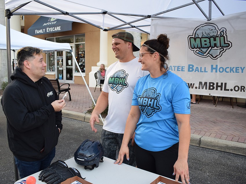 Joe Riggio of Del Tierra hears about the new Manatee Ball Hockey League from Bradley and Rebecca Gustafson at Music on Main.