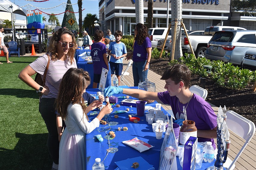 Malanie Morillo looks on as Darien Christensen (right) puts a chocolate topper on an edible dreidel for Emma Lindsey of Parrish.