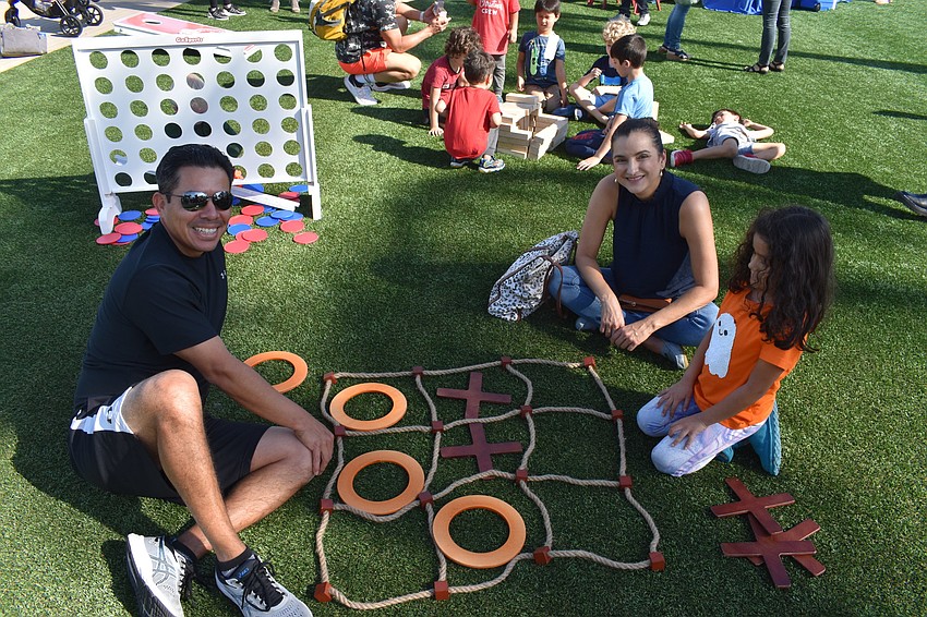 Mario, Jessica and Anabela Bringas of Sarasota play a game of tic-tac-toe on the grass.