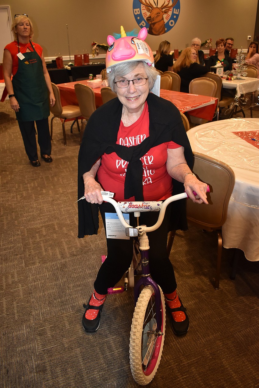 Lakewood Ranch resident Veletta Tusa playfully poses with the girls' bike and helmet she won at the raffle. Tusa joked that she would be riding the bike, which was equipped with training wheels, around her community.